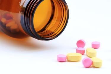 gule og lyserøde piller ved siden af pilleglas